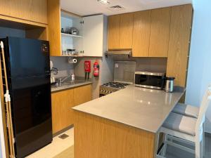 une cuisine avec un réfrigérateur noir et des armoires en bois dans l'établissement Royal Vacation Home - Modern 1BR, à Charjah 8 autres photos