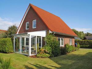 ein kleines Haus mit einem orangenen Dach und einem Hof in der Unterkunft Holiday Home in Butjadingen near Wadden Sea in Burhave