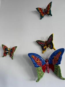 four colorful butterflies sitting on a white wall at Apartamento La casa Verde in Punta Prima