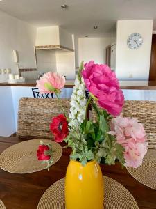a yellow vase filled with flowers on a table at Apartamento La casa Verde in Punta Prima
