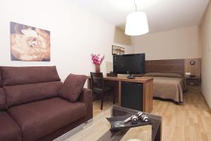 ein Wohnzimmer mit einem Sofa und einem Tisch mit einem TV in der Unterkunft Hotel Mar de Plata in Sarria