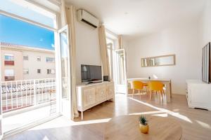 Una sala de estar con un televisor y una mesa con sillas. en Bel appartement avec balcon centre ville, en Cannes