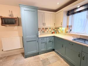 a kitchen with blue cabinets and a window at Misty View - 2 Bed Cottage in Winchcombe in Winchcombe +24 photos