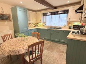a kitchen with green cabinets and a table with a tableablish at Misty View - 2 Bed Cottage in Winchcombe in Winchcombe