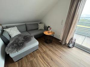 a living room with a gray couch and a table at Ferienwohnung Schneider in Weiler-Simmerberg