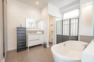 Un baño con bañera, lavabo y espejo. en Bel appartement avec balcon centre ville, en Cannes 6 fotos más