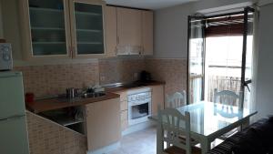 a kitchen with a sink and a table and a refrigerator at Apartamento OGUM Cáceres in Cáceres