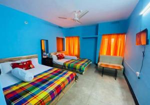 a blue bedroom with two beds and a chair at The Hotel Golden Star in Khulna