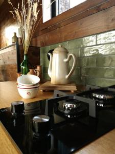 Una cocina con una estufa y una tetera sobre una encimera. en La Tiny House de La Rivière, en Sceaux-du-Gâtinais 12 fotos más