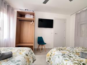 a bedroom with two beds and a tv on the wall at Apartamento Asia - Amplio, céntrico y muy luminoso in Almansa