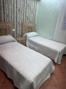 a room with two beds with white blankets on them at Marinasmir Jawhara in Fnidek