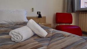 a bed with wrapped towels on it with a red chair at Galli's House - 30' Milano, 7' Malpensa in Busto Arsizio +8 photos