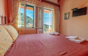 a bedroom with a red bed with a large window at Charming Studio Just Steps from Paramonas Beach in Paramonas