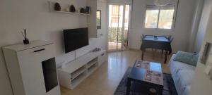 a white living room with a tv and a couch at Casa Dolores in Puerto de Mazarrón