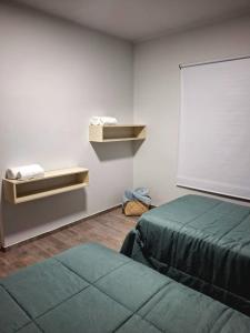 a room with two beds and a white wall at Rincón de paso in Ciudad Lujan de Cuyo +2 photos