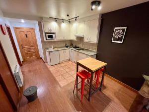 eine Küche mit einem Tisch und zwei roten Hockern in der Unterkunft Lotila Flats Cuirgu in Felechosa