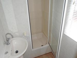a white bathroom with a shower and a sink at Mobile Home in Rogowo near Baltic Beach in Mrzeżyno +24 photos