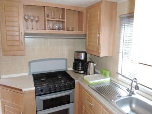a kitchen with a stove top oven next to a sink at Mobile Home in Rogowo near Baltic Beach in Mrzeżyno