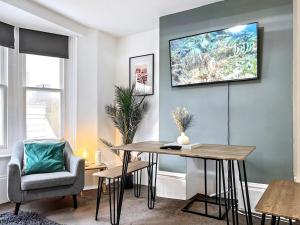 a living room with a table and a tv on the wall at The Seaside Snug in Brighton & Hove +1 photo