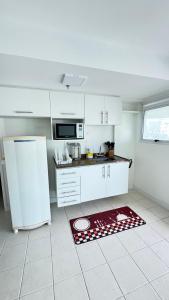 a kitchen with a white refrigerator and a red rug at Apart completo RESORT Pé na Areia RECREIO in Rio de Janeiro