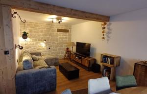 a living room with a couch and a tv at Chez Bernadette in La Bresse
