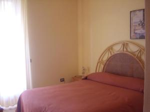 a bedroom with a bed with pink sheets and a window at B&B Valoroso Village in Licata
