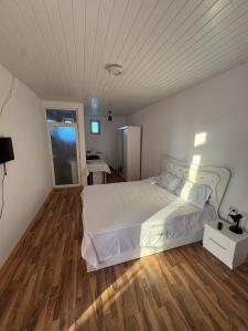 une chambre avec un lit blanc et un parquet dans l'établissement Garsoniera la vila, à Jilava