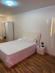 - une chambre avec un lit blanc et une couverture rose dans l'établissement Garsoniera la vila, à Jilava