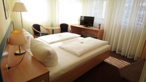 a hotel room with a bed and a desk and a window at Central Hotel Winnenden in Winnenden