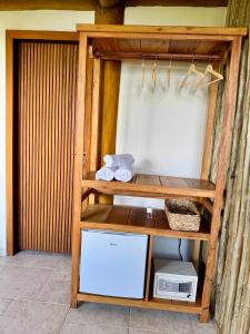ein Holzregal mit einem Kühlschrank in einem Zimmer in der Unterkunft Suíte Deluxe com vista para Ilhabela in São Sebastião