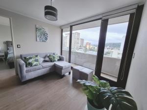 a living room with a couch and a large window at Monstera, Depto 6 personas edificio Centro Lagos II in Temuco
