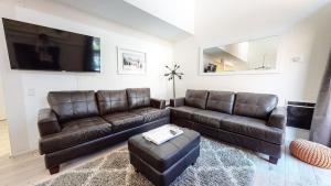 a living room with brown leather furniture and a flat screen tv at Walk to Canyon Lodge Ski back Modern Space in Mammoth Lakes