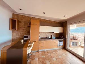 a kitchen with wooden cabinets and a large window at Golden Sea View -Thasos House in Skala Potamias +26 photos