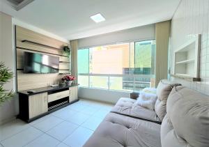 ein Wohnzimmer mit Couch und Flachbildfernseher in der Unterkunft 2 quartos, suíte, perto do mar, com ar e garagem! in Capão da Canoa