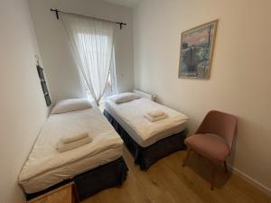 two beds in a room with a chair and a window at APARTAMENT POLANICA RESIDENCE Nr 1 in Polanica-Zdrój