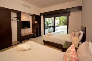 a hotel room with two beds and a television at Awesome apartment at Aldea Thai Beachfront in Playa del Carmen +108 photos