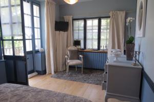 1 dormitorio con escritorio, silla y ventanas en Demeure d'Hôtes L'Hermitage, en Mouxy