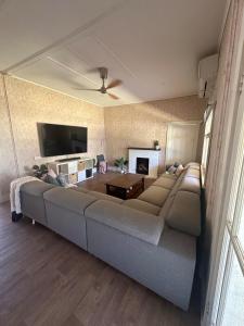 ein Wohnzimmer mit einem großen Sofa und einem Fernseher in der Unterkunft Cottage in Barmera in Barmera + 6 Fotos