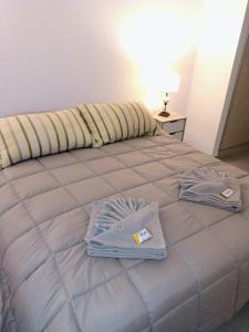 a bed with two towels on top of it at Puerto Madryn Temporarios- Frente al Mar in Puerto Madryn