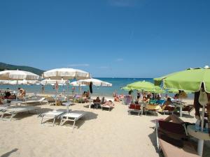 a group of people sitting on a beach with umbrellas at Villa Casa Rosa in Procchio