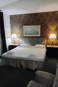 a bedroom with a bed and two lamps and a chair at Hotel Bella Vista Warszawa in Warsaw