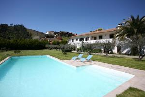 a swimming pool with two chairs and a house at Quinta Madureira in Alfolões