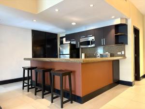 eine Küche mit schwarzen Schränken und Barhockern in der Unterkunft Awesome apartment at Aldea Thai Beachfront in Playa del Carmen