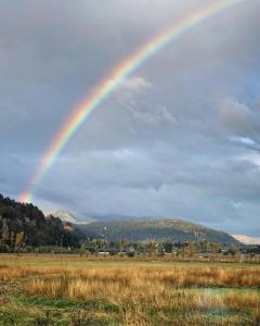 a rainbow in the sky over a field at TRAVELLERS Camping & Dorms in San Martín de los Andes