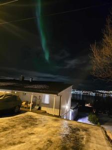 a house with a green northern lights in the sky at Koselig leilighet over to plan. in Tromsø