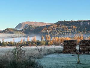 an old log cabin in a field with a mountain at TRAVELLERS Camping & Dorms in San Martín de los Andes