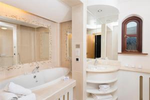 a bathroom with a tub, sink and mirror at Delphi Resort Hotel & Spa in Leenaun
