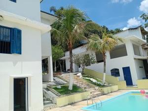 a house with a swimming pool and palm trees at Chacara porta do mundo in Suzano