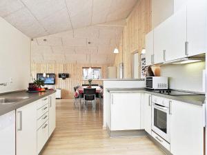 a kitchen with white cabinets and a dining room at Luxury Beach House for 14 - By Traum Ferienwohnungen in Løkken +45 photos