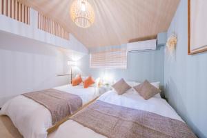 two beds in a room with a ceiling at おそば 露天風呂でリラックス ベッド7台 usjへ11分 商店街に位置するお宿 in Osaka